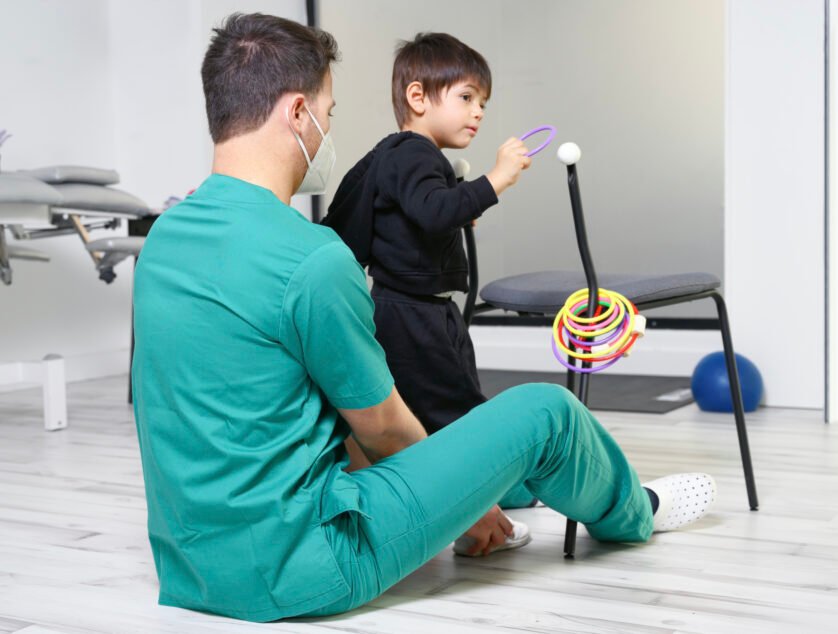 Child with cerebral palsy on physiotherapy in a children therapy center. Boy with disability doing exercises with physiotherapists in rehabitation centre. High quality photo.